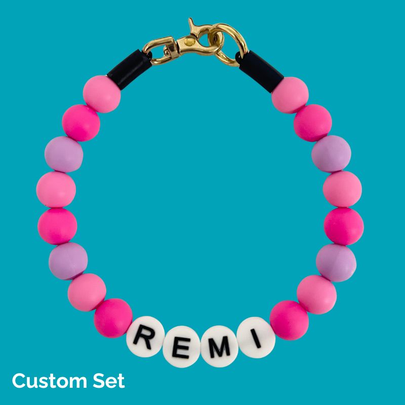 Bracelet with pink and purple beads and 'REMI' letters on a blue background