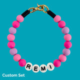 Bracelet with pink and purple beads and 'REMI' letters on a blue background