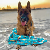 German Shepherd lying on Salty Paws Surf's Up Adventure Dog Towel sand free in teal at the beach during sunset