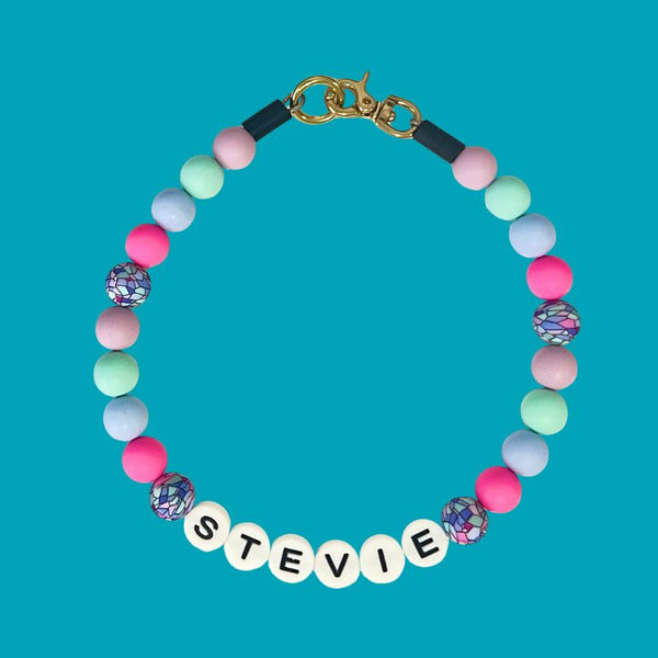 Colorful beaded bracelet with name tag 'STEVIE' on a blue background