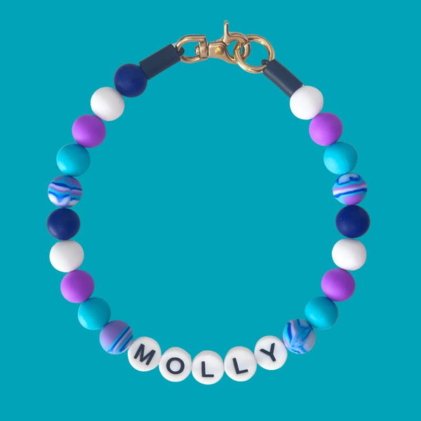 Colorful beaded bracelet with 'MOLLY' on a blue background