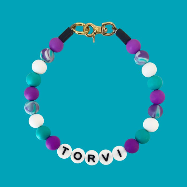 Colorful beaded bracelet with 'TORVI' on a blue background