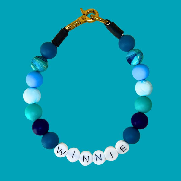 blue and green beads and 'Winnie' charm on a turquoise background
