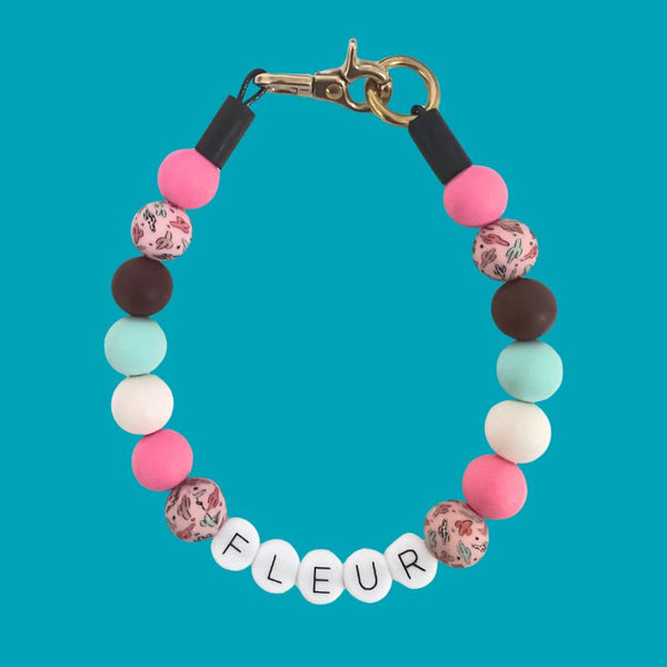 Colorful beaded bracelet with floral and solid beads on a turquoise background